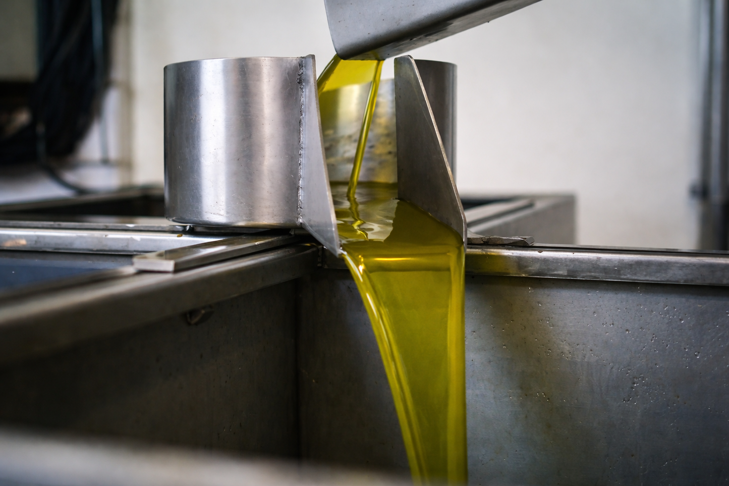 Fresh extra virgin olive oil flowing from stainless steel extraction system during production